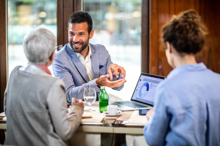 Financial adviser explaining business strategy to two female business partners in a restaurant