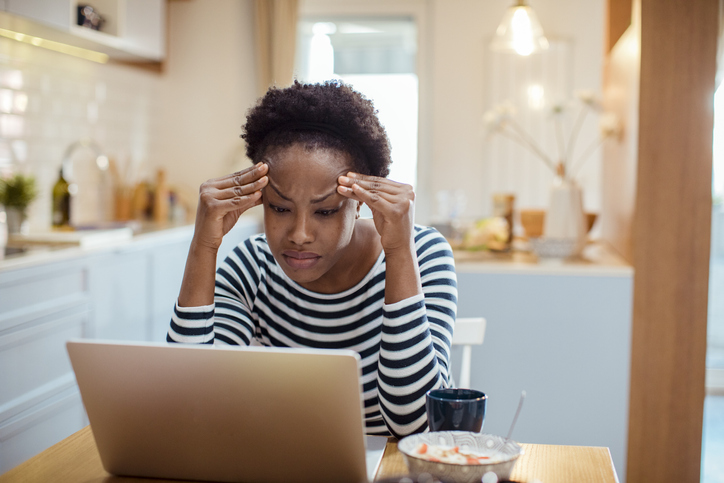 Young adult woman using a laptop while having breakfast