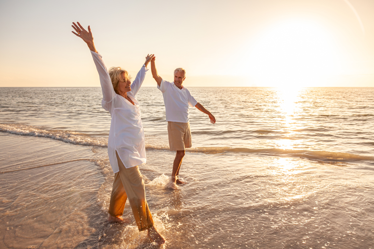 retired couple on a beach paddling in the sea